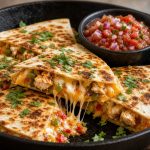 Chicken quesadilla cut into wedges with melted cheese and salsa