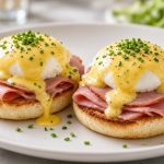 Eggs benedict on an English muffin with ham, poached egg, and hollandaise
