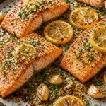 Baked salmon fillets with lemon slices, garlic, and herbs