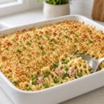 Tuna noodle casserole with peas and a golden breadcrumb topping in a 9x13 dish